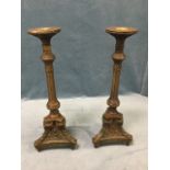 A pair of heavy brass candlesticks with leaf cast classical columns on triangular bases, with rams