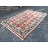 An Indian thick-pile wool rug woven with trelliswork of floral medallions on pink field, framed by