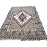 An Indian rug woven with diamond shaped floral medallion on ivory ground framed by hooked borders,