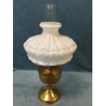 A late Victorian brass oil lamp, the Famous model with embossed milk glass shade around a chimney,