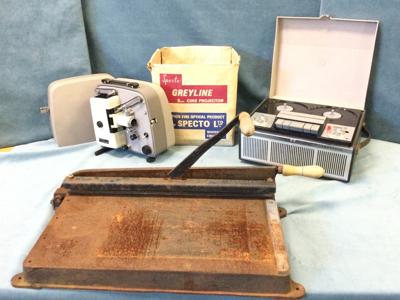 A large cast iron table guillotine with wood handles; a 60s Ferguson reel-to-reel tape recorder; and