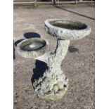 A composition stone two-tier birdbath cast in the form of treetrunk with circular basins, raised