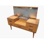 A mid-century dressing table with rectangular mirror above a well with glass shelf, the cabinet with
