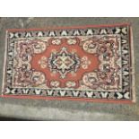 A small oriental style rug woven with floral medallion and scrolled spandrels on pink field,