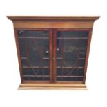 The top of a mahogany bookcase cabinet, with moulded ogee cornice above astragal glazed doors