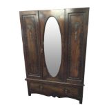 An oak wardrobe with oval bevelled mirror door flanked by beaded panels with applied shell