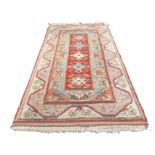 A wide Turkish wool runner woven with five hooked diamond shaped floral medallions on red field