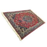 An oriental rug woven with central lozenge medallion on red field with conforming spandrels, the
