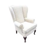 A contemporary upholstered wing armchair with padded back and arms above a loose cushion on sprung