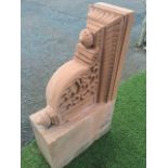 A large carved red sandstone corbel, the bracket with blind fretwork leaf scrolled sides beneath a