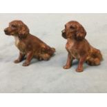 A pair of cold painted bronze spaniels, the animals seated on their haunches with inset glass