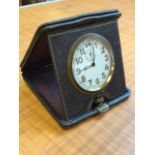 A square leather cased Edwardian travel clock with Swiss movement and clear enamelled dial under