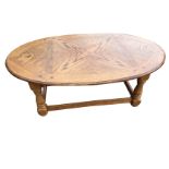 An oval oak coffee table, the moulded quarter veneered top above waved side aprons, supported on