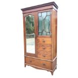 An art nouveau mahogany bedroom cabinet with moulded dentil cornice above an astragal glazed door