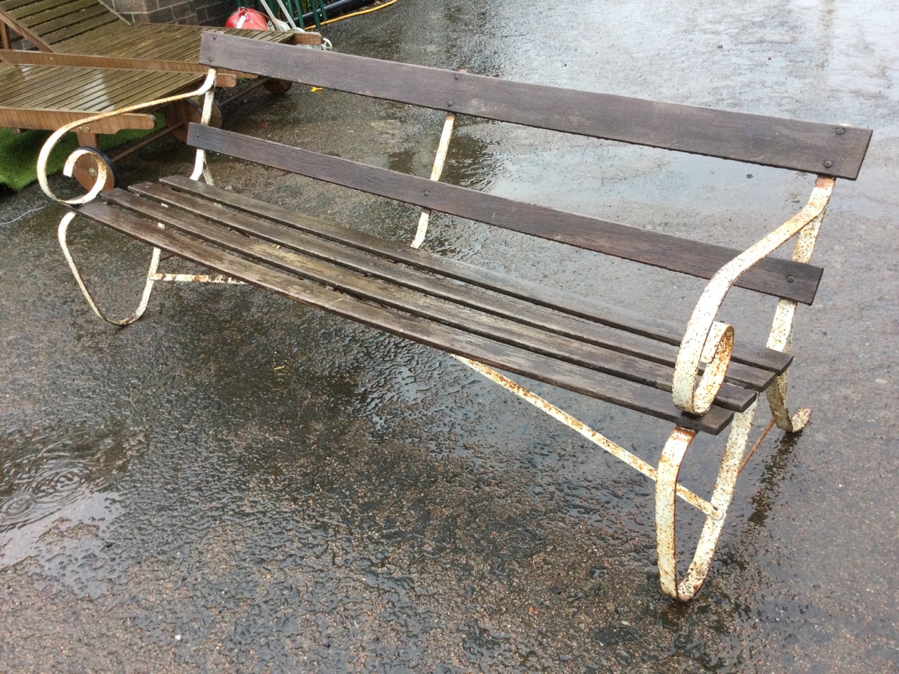 An Edwardian 6ft wrought iron garden bench with slatted back and seat, the ends with scrolled arms