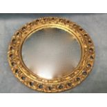 A circular convex mirror in leaf carved pierced giltwood frame. (16in dia ext)