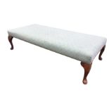 A rectangular upholstered low stool, the seat raised on stained cabriole legs. (48.5in x 23.25in x