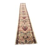 An Axminster style runner woven in the oriental manner with diamond shaped red floral lozenges and