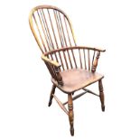 A nineteenth century elm windsor chair with hoop back on spindles above bow arms and solid seat,