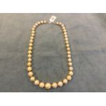 A pearl necklace with fourty-three individually knotted graduated golden pearls, with platinum
