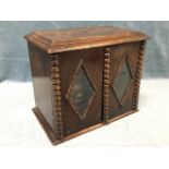 A C20th oak smokers cabinet with moulded top above bead mounted doors with diamond lozenge glazed