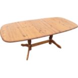 A contemporary extending pine dining table, the rounded rectangular top sliding to accommodate a