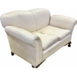 An Edwardian upholstered drop-arm two-seater sofa, with padded back above loose cushions, the sprung