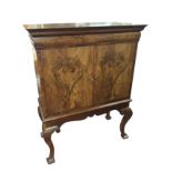 A Queen Anne style walnut cabinet on stand, with moulded cornice above a long cushion frieze drawer,