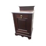 A stained Edwardian fireside cupboard with moulded top above a panelled drop-down coal compartment