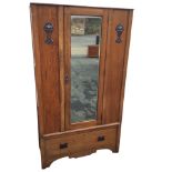 An art nouveau oak wardrobe with central bevelled mirror door framed by panels with applied anodised
