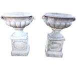 A pair of large composition stone urns, the vessels with overhanging cushion rims and scrolled