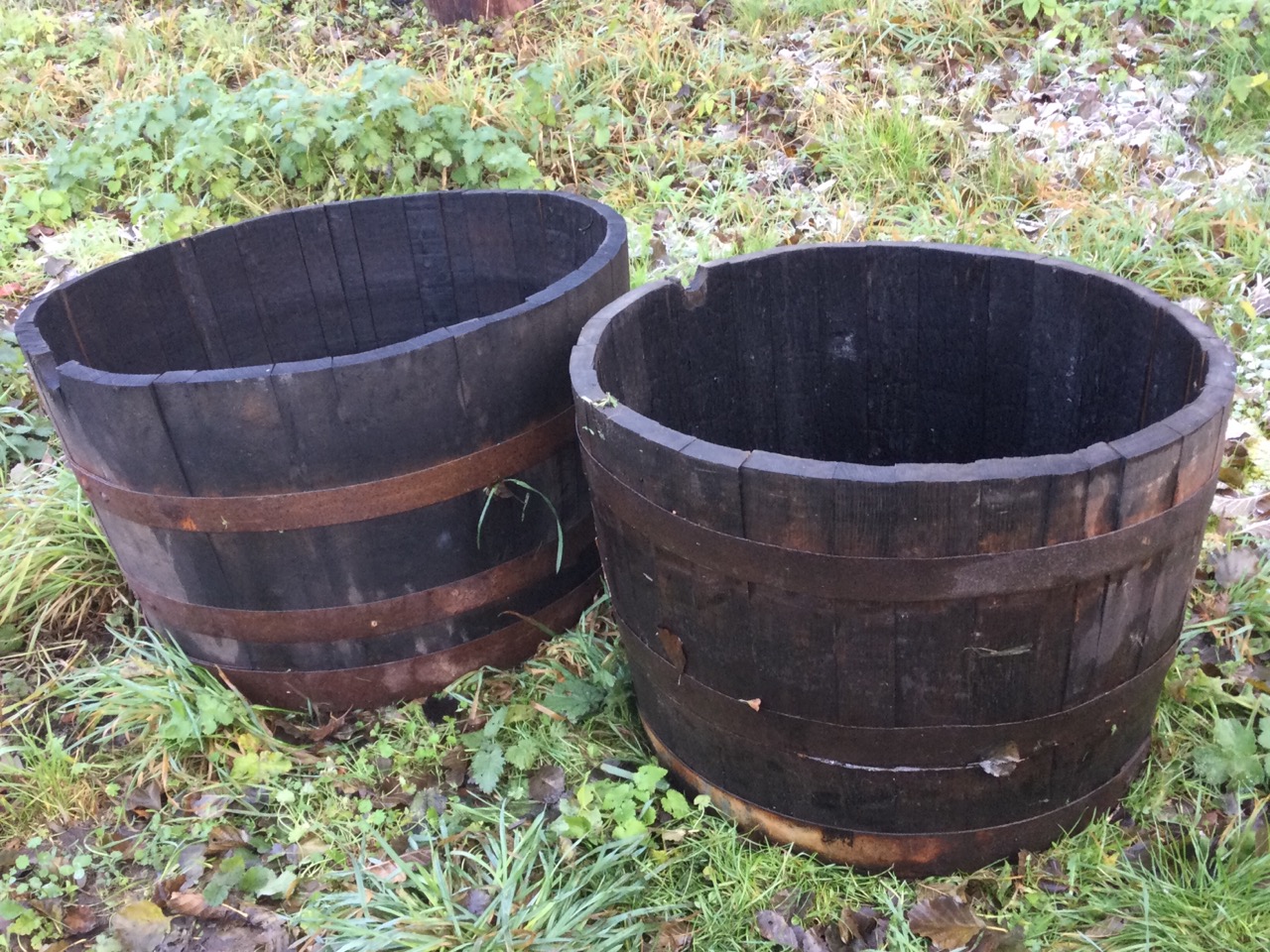 A graduated pair of oak garden barrel tubs, the staves bound by riveted metal strap bands. (24in &