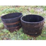 A graduated pair of oak garden barrel tubs, the staves bound by riveted metal strap bands. (24in &