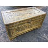 A carved oriental box, the lid and front panel with figural landscapes scenes framed by floral