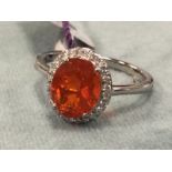 A platinum fire opal ring, the claw set oval Salamanca fire opal framed by border of small diamonds,