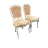 A pair of painted Louis VI style side chairs, the cane backs with floral carving above sprung