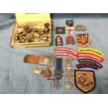 An old cigar box containing a collection of military badges, buttons, cloth embroidered regimental