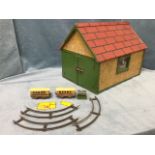 A painted childs toy garage with pitched roof, the doors opening with pair of O gauge carriages,