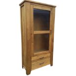 A contemporary oak cabinet with wide glazed door enclosing glass shelves above two drawers, the