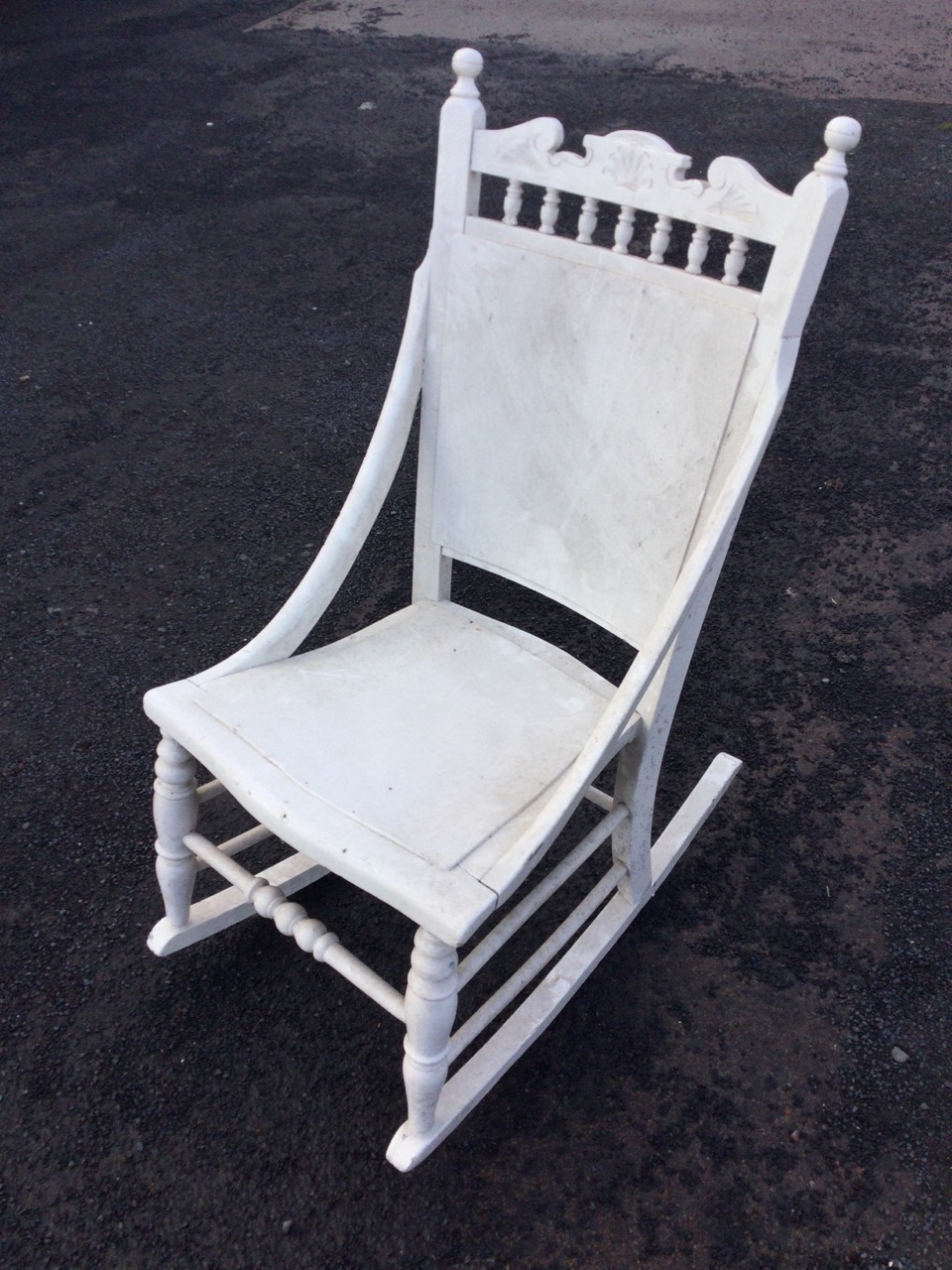 A late nineteenth century painted rocking chair with spindle gallery to back beneath a carved