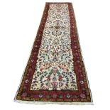 A Persian wool runner with multi-floral ivory field framed by blue frieze of linked flowerheads