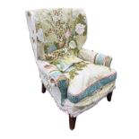 A Georgian style upholstered wing armchair with padded back and loose cushion above a sprung seat,