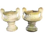 A pair of composition stone garden urns with moulded scrolled handles to waisted bowls, raised on