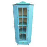 A painted pine corner cabinet with arched pediment above a long astragal glazed door with drawer