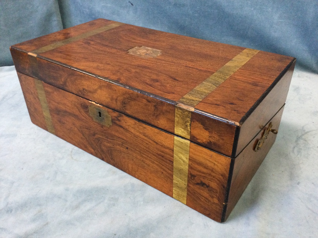 A Victorian walnut writing box with brass banding and escutcheon, having ebonised corner mouldings -