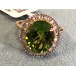 A 9ct gold ring set with rare natural Hebei peridot, the large oval claw set stone above a border of