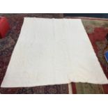 A large white cotton Durham quilt, hand-sewn in an embossed floral quilted pattern. (78in x 104in)