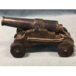 An iron starter canon, the tapering 5.75in barrel on oak carriage, the pommel with makers monogram