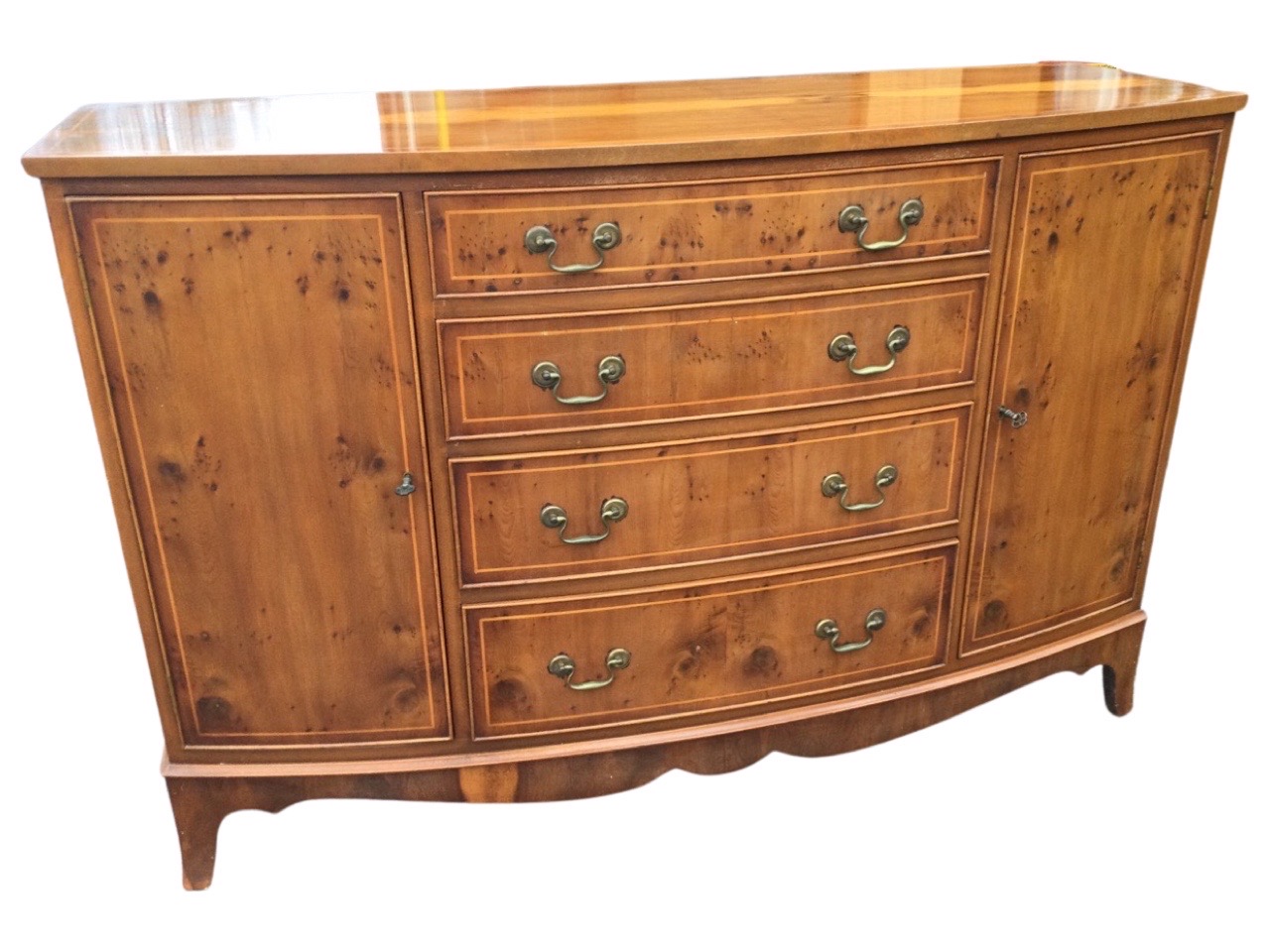 A bowfronted yew sideboard, the crossbanded top, drawers and cupboards all inlaid with boxwood