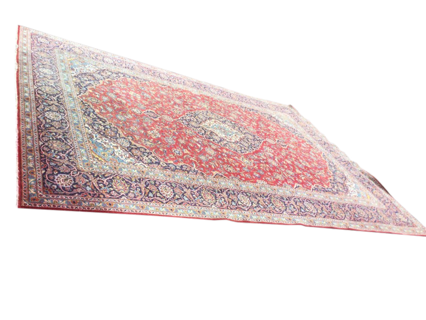 A large Indian carpet woven with ink blue spandrels and conforming central floral medallion on